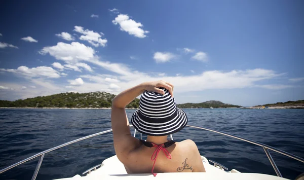 Jovem com chapéu sentado na frente de um barco à vela — Fotografia de Stock