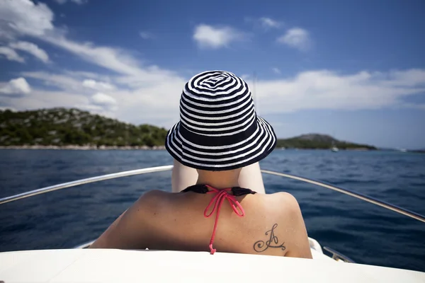 Νεαρή γυναίκα με καπέλο που κάθεται στο μπροστινό μέρος της μια βάρκα πανί — Φωτογραφία Αρχείου