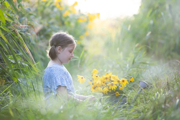 Kleines Mädchen Sitzt Mit Einer Mit Herbstblumen Gefüllten Gießkanne Auf — Stockfoto