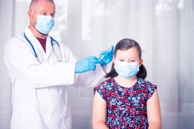Çocuklar aşılama konsepti. Doktor yüz maskesi takan küçük bir kızın koluna aşı yapıyor..