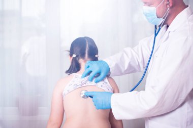 Çocuk doktoru klinikteki küçük kızı muayene ediyor. Çocuk tıbbi bakım konsepti.