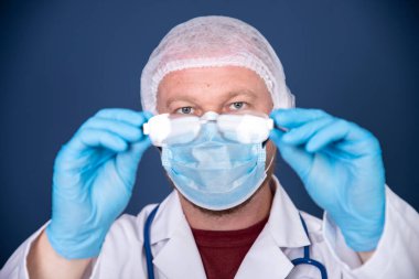 Medicine, profession and healthcare concept - close up of male doctor or scientist in protective facial mask over blue background