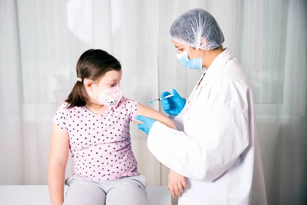 予防接種の概念を子供 顔マスクをした少女の腕の中で予防接種を注入医師 ロイヤリティフリーのストック画像