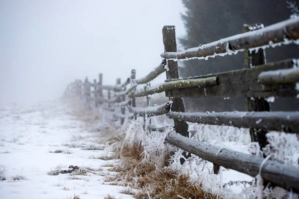 雪に覆われた霧の冬の風景の中に霜が降り 凍結した木製のフェンス — ストック写真
