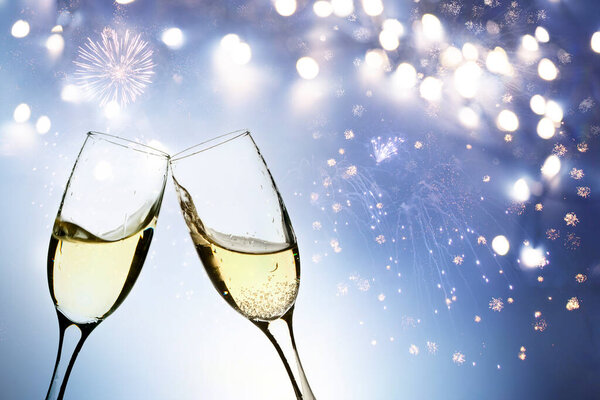 Glasses with champagne against fireworks and holiday lights
