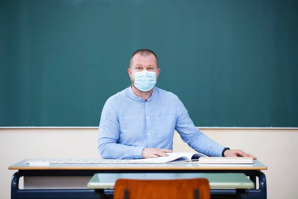 Teacher in the classroom wearing mask. Learning during coronavirus pandemic concept.