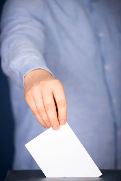 Hand of a voter putting vote in the ballot box. Election concept.