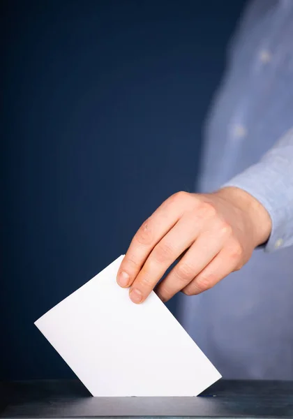 Hand of a voter putting vote in the ballot box. Election concept.