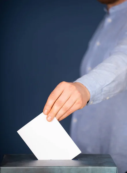 Hand of a voter putting vote in the ballot box. Election concept.