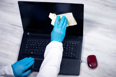 Ofis, dizüstünü dezenfektanla temizliyor. Coronavirus COVID-19 temizlik ve çalışma masasının dezenfeksiyonunu temizleyin..