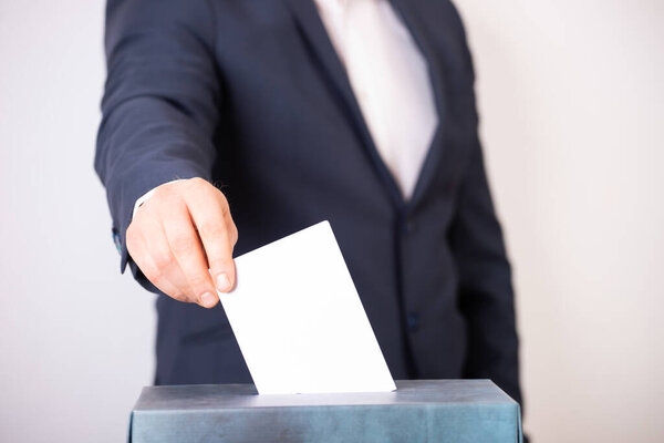Рука избирателя, голосующего в урне для голосования. Концепция выборов.