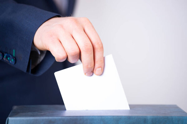 Рука избирателя, голосующего в урне для голосования. Концепция выборов.
