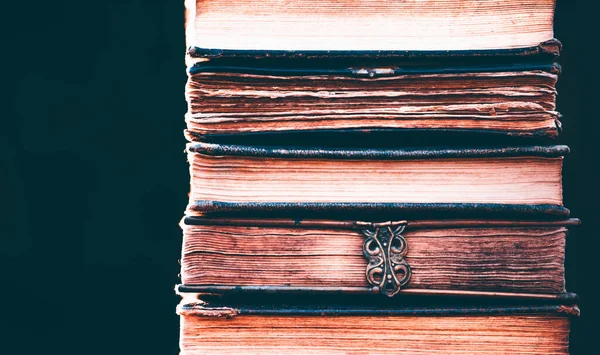 Literature, reading concept: banner or header image with stack of antique books against a dark background