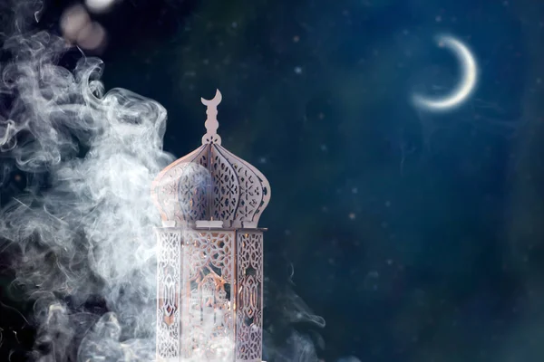 Ornamental Arabic lantern with crescent moon glowing at night. Festive greeting card for Muslim holy month Ramadan Kareem.