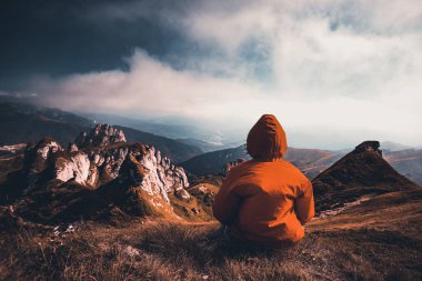 Uçurumda oturan kadın, dağların manzarasının tadını çıkarıyor. Yaşam tarzı konsepti. Aktif macera seyahatleri.