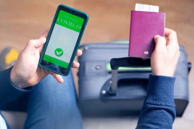 Aşılanmış kişi covid-19 salgını sırasında seyahat için cep telefonunda dijital sağlık pasaport uygulaması kullanıyor.