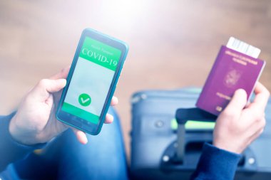 Aşılanmış kişi covid-19 salgını sırasında seyahat için cep telefonunda dijital sağlık pasaport uygulaması kullanıyor.