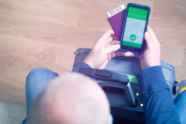 Aşılanmış kişi covid-19 salgını sırasında seyahat için cep telefonunda dijital sağlık pasaport uygulaması kullanıyor.