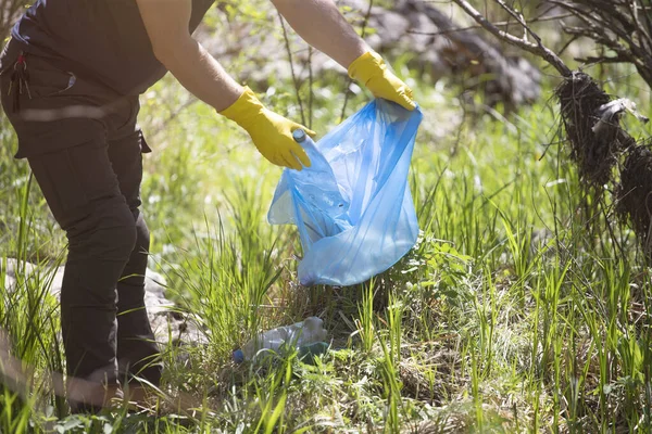 Hand picking up garbage plastic for cleaning the woods or parks. Environmental protection, Earth Day, volunteer concept.