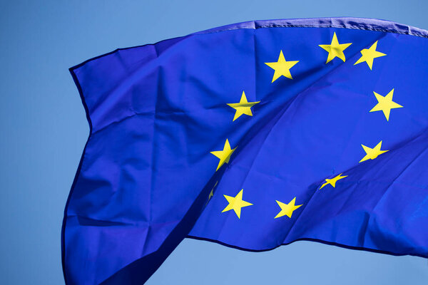 Waving European Union flag on blue sky.