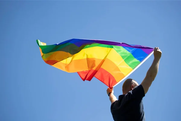 Uomo Che Tiene Una Bandiera Gay Arcobaleno Sopra Cielo Blu — Foto Stock