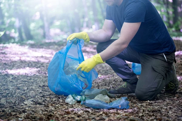 Hand picking up garbage plastic for cleaning the woods or parks. Environmental protection, Earth Day, volunteer concept.