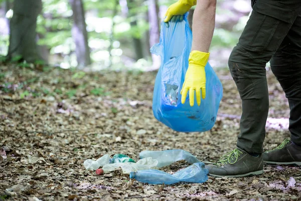 Hand picking up garbage plastic for cleaning the woods or parks. Environmental protection, Earth Day, volunteer concept.