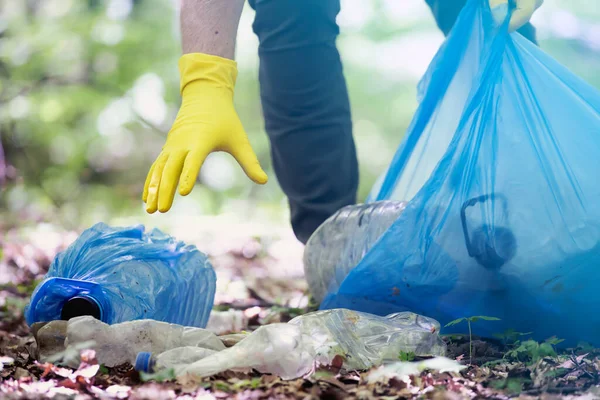 Hand picking up garbage plastic for cleaning the woods or parks. Environmental protection, Earth Day, volunteer concept.