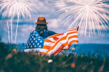 4 Temmuz 'da havai fişeklerin altında Amerikan bayrağını tutan mutlu vatansever genç kız.. 