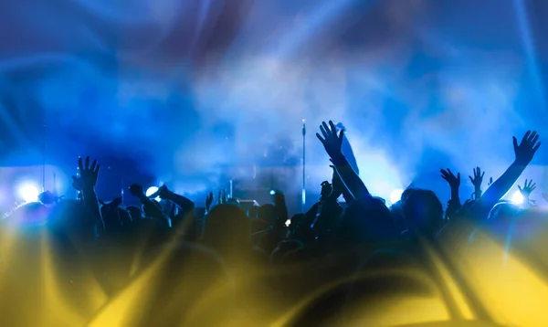 Football fans supporting Ukraine - crowd celebrating in stadium with raised hands against Ukraine flag