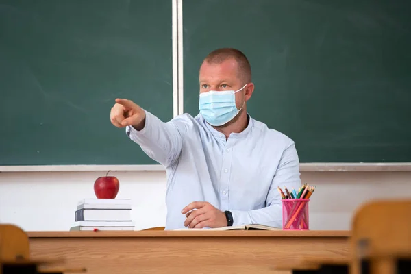 Teacher with mask in the classroom. Social distanting and classroom safety during coronavirus epidemic