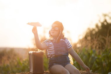 Pilot kaskıyla oynayan mutlu çocuk havacı gibi davranıyor. Seyahat, tatil ve özgürlük kavramı. Çocukluk, hayal gücü, hayal gücü.