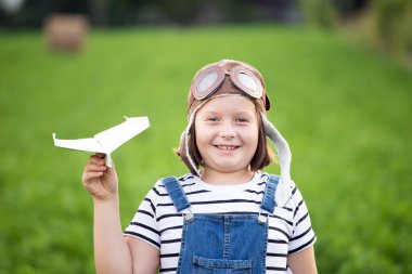 Pilot kaskıyla oynayan mutlu çocuk havacı gibi davranıyor. Seyahat, tatil ve özgürlük kavramı. Çocukluk, hayal gücü, hayal gücü.