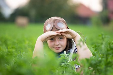 Pilot kaskıyla oynayan mutlu çocuk havacı gibi davranıyor. Seyahat, tatil ve özgürlük kavramı. Çocukluk, hayal gücü, hayal gücü.
