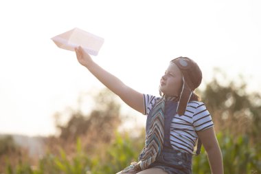 Pilot kaskıyla oynayan mutlu çocuk havacı gibi davranıyor. Seyahat, tatil ve özgürlük kavramı. Çocukluk, hayal gücü, hayal gücü.