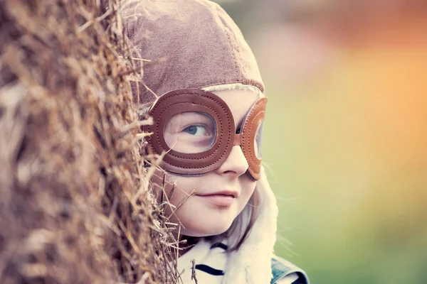 Pilot kaskıyla oynayan mutlu çocuk havacı gibi davranıyor. Seyahat, tatil ve özgürlük kavramı. Çocukluk, hayal gücü, hayal gücü.