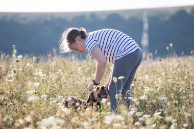Yaz günbatımında köpeğiyle oynayan ve antrenman yapan bir çocuk.