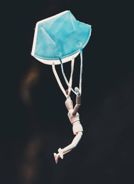 Tahta figür koruyucu maskeyle uçuyor. Coronavirus veya covid-19 virüs enfeksiyonu konsepti. 