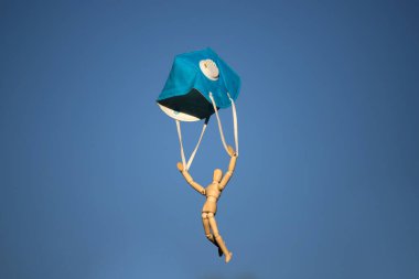 Mavi gökyüzünde koruyucu maskeyle uçan tahta bir figür. Coronavirus veya covid-19 virüs enfeksiyonu konsepti. 