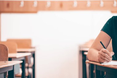 Lise ya da üniversite öğrencisi elinde kalem kağıdıyla cevap kağıdı tutuyor. Final sınavı konsepti.