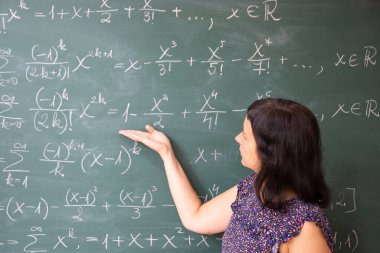 Okulda matematik dersi sırasında tahtada açıklayan öğretmen ya da öğrenci.