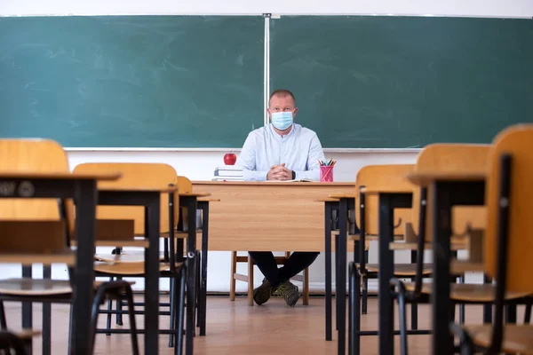 Teacher with mask in the classroom. Social distanting and classroom safety during coronavirus epidemic