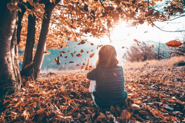 Günbatımında sihirli sonbahar manzarasında küçük bir kız. Eğleniyor, sonbahar konseptinde seyahat ediyor..