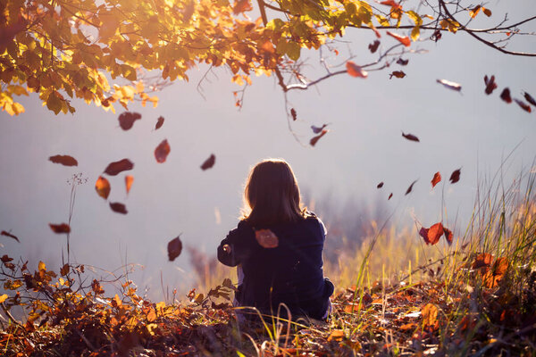 Little girl in magic autum landscape in the sunset. Enjoying, traveling in autumn concept.
