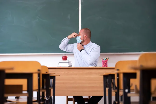 Teacher with mask teaching how to wear mask at school. Social distanting and classroom safety during coronavirus epidemic