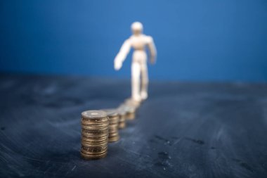 Tahta adam artan madeni paraların üzerinde uyanıyor. Sıkı çalışma kavramı, finansal büyüme.