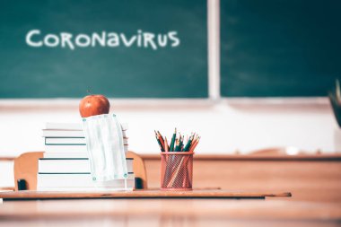 Coronavirüs salgınından sonra okula döndüm. Okul kırtasiyesi malzemeleri, tıbbi maskeler karatahta altyapısı ve koronavirüs metni..