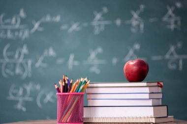 Okul Konseptine geri dönelim. Elma, aksesuarlar ve karatahtaya karşı kitaplar.