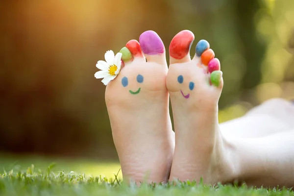 孩子的脚在绿草上画着五彩缤纷的笑脸 — 图库照片