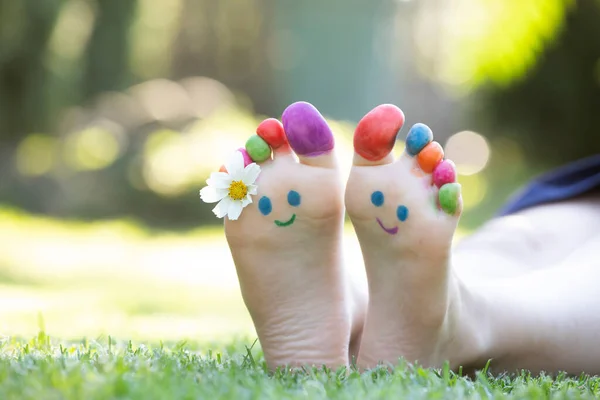 Dětské Nohy Malované Barevným Úsměvem Tvář Zelené Trávě — Stock fotografie